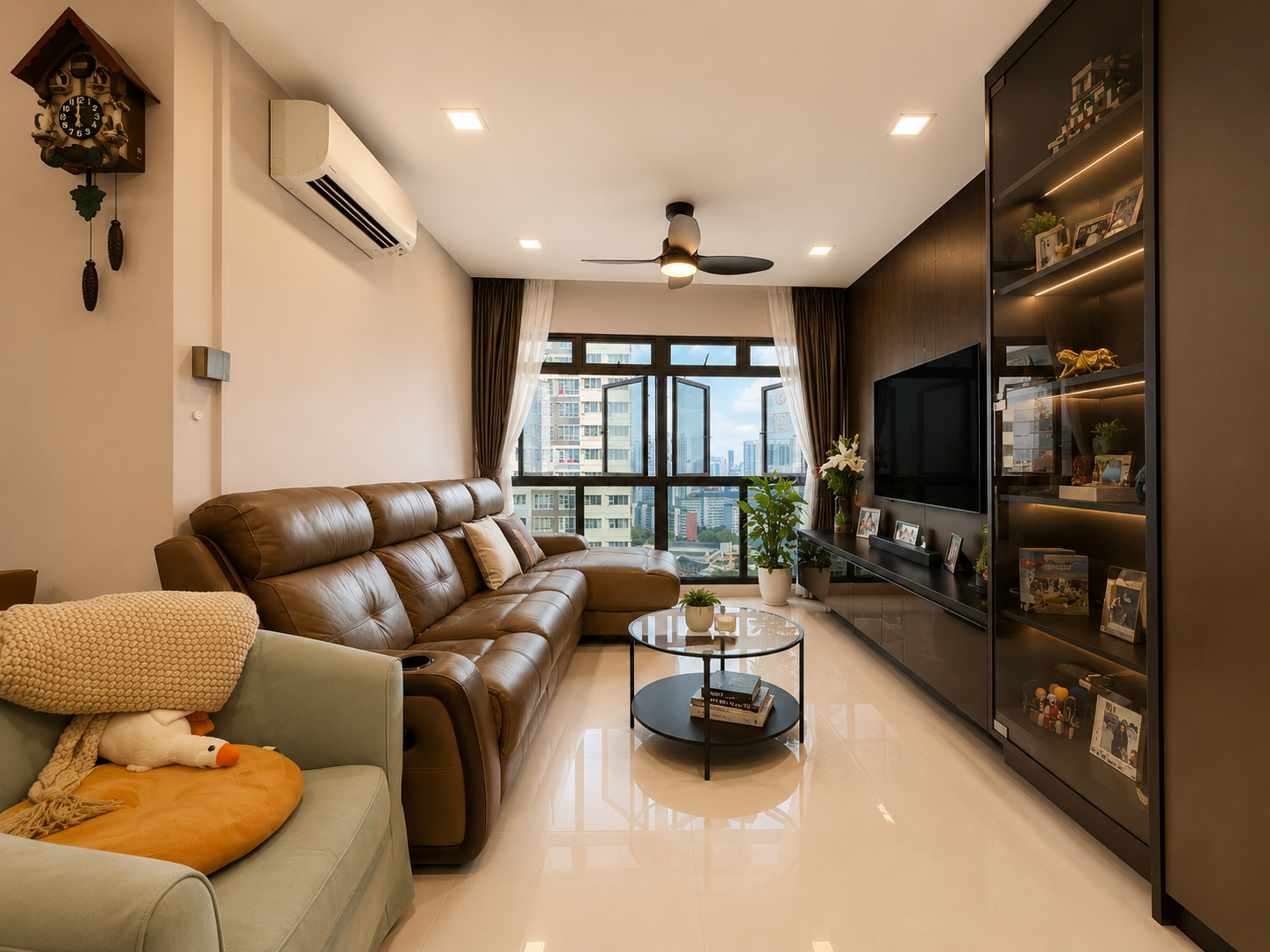 Living room at 18 Jalan Tenteram with leather sofa, feature TV wall and corner windows framing a high-floor city-fringe view
