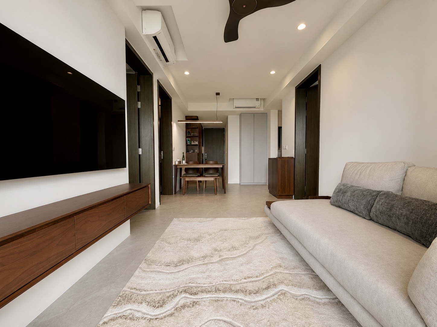 AMO Residence living room with wall-mounted TV, walnut console and dining area beyond