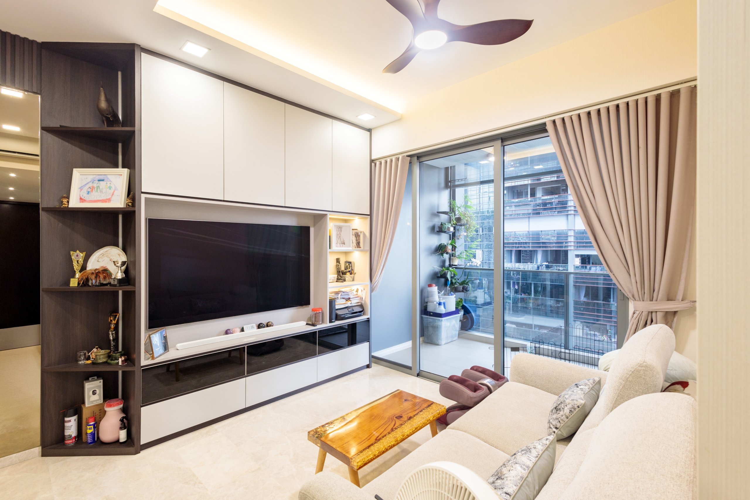 JadeScape living room with white and dark-wood built-in TV feature wall, ceiling fan and balcony access